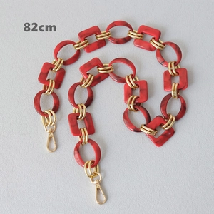 Close-up of red marble acrylic chain strap with gold metal rings and spring clasps