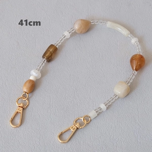Detail view of 41cm acrylic beaded chain with gold metal hooks on grey background