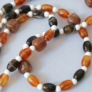 Détail macro de perles en résine ambrée et pierres texturées avec séparateurs en métal doré