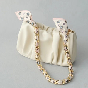 Detail of silk scarf intertwined with gold chain strap on beige ruched leather bag