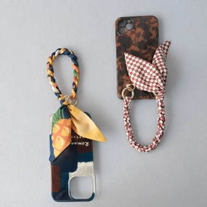 Détail de la dragonne de téléphone tissée avec motif foulard en soie et anneau doré