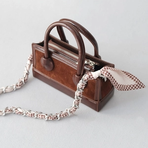 Close-up of a brown tote bag with metal chain strap and houndstooth scarf detail