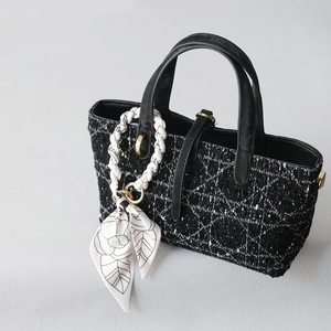 Detail of black and white tweed handbag with quilted texture and flower print silk scarf