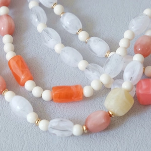 Gros plan sur chaîne de perles acryliques colorées avec résine orange et métal doré