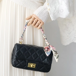 Close-up of quilted black leather handbag handle wrapped with floral silk scarf
