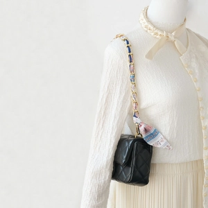 Macro detail of quilted black leather mini bag with gold chain and floral scarf wrap