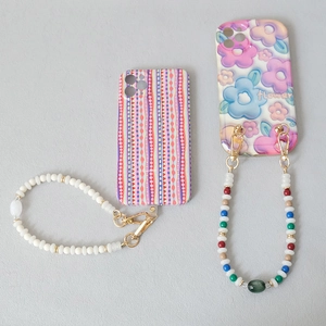 Detail of colorful acrylic bead phone straps with metal clasps on patterned cases