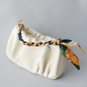 Détail du sac plissé crème en similicuir avec poignée tressée et foulard en soie