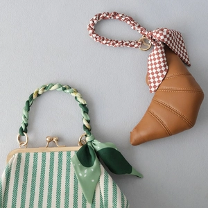 Détail du sac en toile verte avec foulard en soie et sac croissant en cuir marron