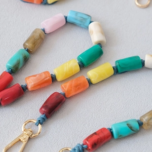 Gros plan de perles acryliques colorées à texture marbrée et fermoir mousqueton doré