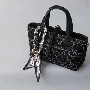 Détail d'un sac à main en tweed avec motif cannage et anse décorée d'un foulard en soie