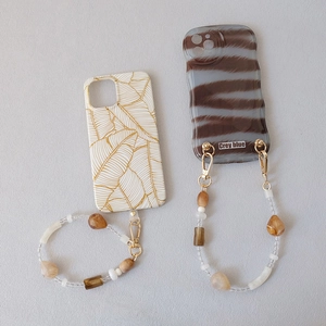 Detail view of acrylic bead chains with metal clips on marble-patterned phone cases
