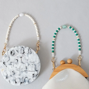 Detailed texture of marble acrylic beads and snakeskin pattern handles on chic handbags