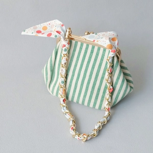 Detail of green striped mini purse with gold metal clasp and colorful silk scarf chain strap