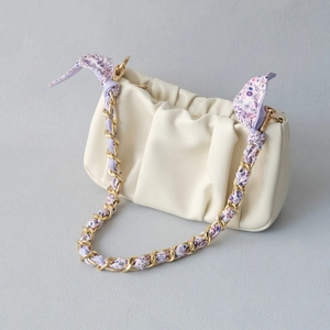 Detailed view of cream clutch bag with gold chain and purple floral silk scarf strap