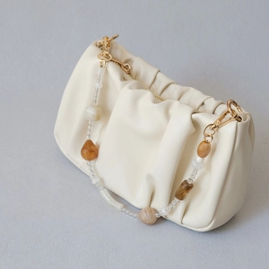 Detail of creamy white pleated cloud bag with elegant marble acrylic bead handle