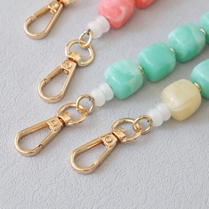 Macro view of colorful acrylic resin bead chains with golden metal lobster clasps