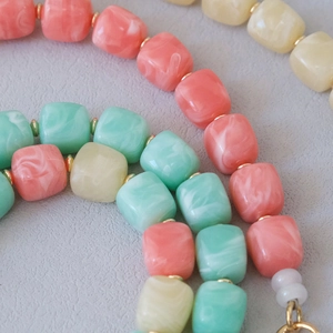 Macro detail of acrylic marble beads in pink and mint with gold spacers and metal clasp