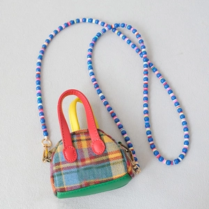 Detailed close-up of a plaid mini pouch with a colorful blue bead strap and leather handles