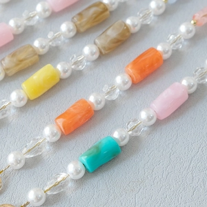 Detail of colorful acrylic beads and pearls on a stylish crossbody phone and bag strap