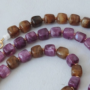 Detail of marble acrylic beads in purple and amber with gold spacers on leather