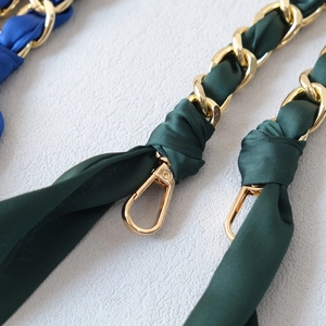 Close-up of golden metal chain straps with woven dark green and royal blue silk