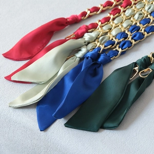 Close-up of silk scarf woven metal chains in red, mint, blue, and green with gold clasps