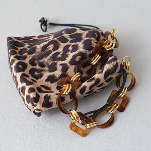 Detail of leopard print drawstring pouch with amber resin chain and gold hardware