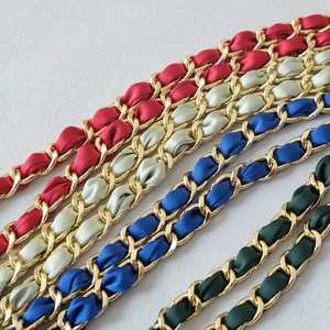 Detail of woven gold metal chain straps with colorful satin ribbons for handbags