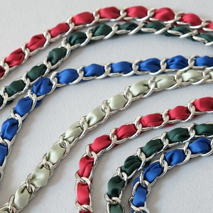 Close-up of woven metal chain straps with colorful satin ribbons for handbags
