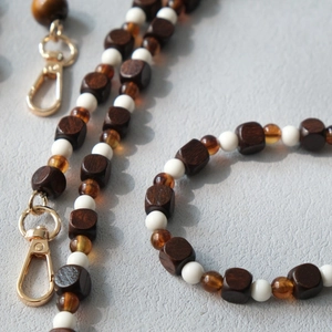 Detailed close-up of amber beads and dark wooden cubes on a stylish crossbody strap