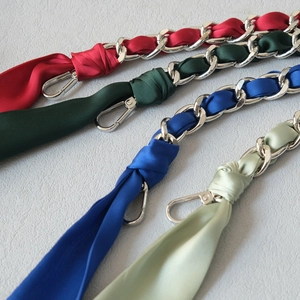 Close-up of silk scarf intertwined with silver chain straps for handbags in vibrant colors