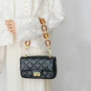 Detail of quilted leather handbag featuring amber resin links and gold chain strap