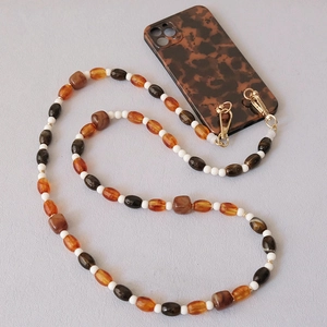 Détail de perles en acrylique ambre et blanc sur une lanière de téléphone avec fermoirs dorés