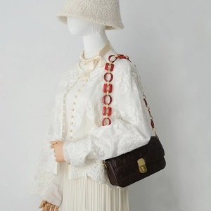 Detail of quilted leather handbag with thick red resin and gold link shoulder strap