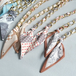 Détail de la bandoulière en chaîne métallique et foulard en soie aux motifs variés
