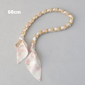 Détail d'une bandoulière de 60cm en chaîne dorée entrelacée d'un ruban de soie floral rose
