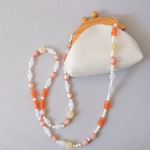 Détail d'un sac serpent blanc avec fermoir bois et bandoulière en perles colorées