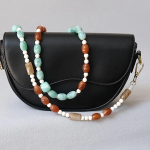 Détail de perles en acrylique colorées et sangle en résine sur sac besace en cuir noir