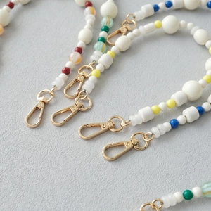Détail de lanières en perles acryliques colorées avec fermoirs dorés et perles marbrées
