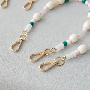 Détail d'une chaîne en perles acryliques colorées avec fermoir doré pour sacs et mobiles