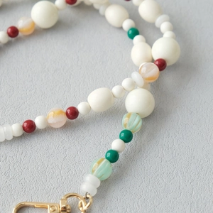 Détail de perles en acrylique colorées et fermoir mousqueton doré sur dragonne chic