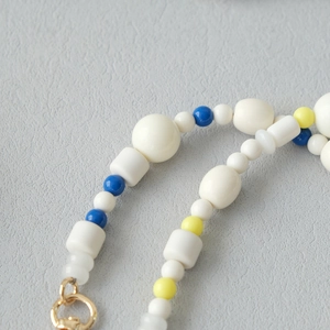 Détail d'une chaîne en perles acryliques colorées avec fermoir mousqueton doré