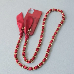 Detail of red silk bow and gold chain strap attached to a matching phone case