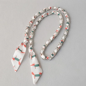Detail of silver chain strap interwoven with white silk scarf featuring fox pattern print