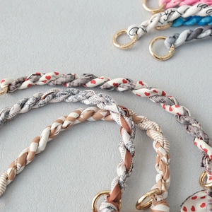 Close-up of hand-woven floral scarf chain strap with golden metal ring for handbags