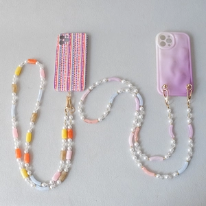 Detail of acrylic bead phone strap with pearls and colorful geometric patterned cases