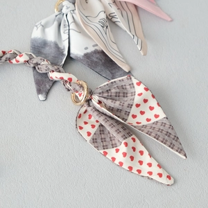 Detail of silk scarf bag chain with heart pattern, lattice texture and golden ring