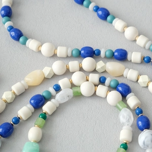 Gros plan de perles acryliques colorées et d'entretoises dorées sur une chaîne bandoulière