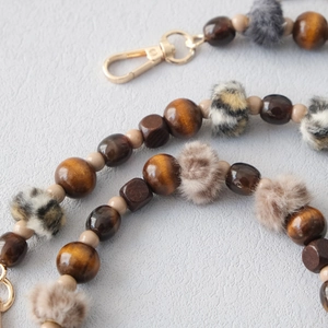 Detailed view of autumn wood beads with faux fur leopard pom-poms and gold lobster clasp